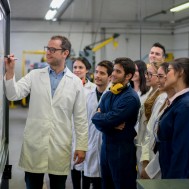 Happy group of engineering students with their teacher writing on the board