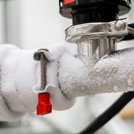 Frozen liquid nitrogen carrying pipes with a valve and black plastic lever close up in a science laboratory 2020