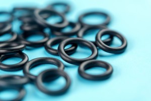 Black elastic rubber o-rings with a round geometric shape on a colored blue background