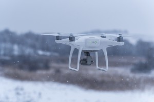 Hovering drone taking pictures of wild nature. Cold winter weather. Cloudy day with falling snow.